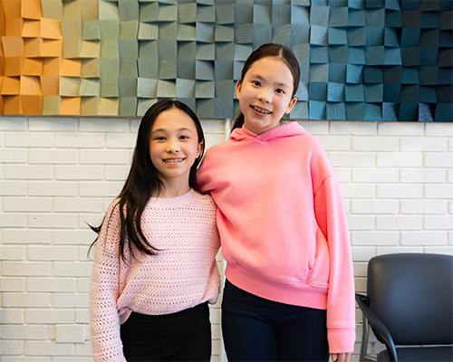 two kids smiling showing off their custom braces from quest orthodontics