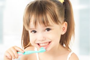 Smiling young girl brushing teeth